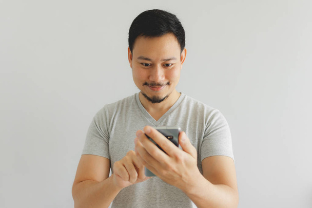 Man in grey t-shirt is using the smartphone. - Foto, Imagen