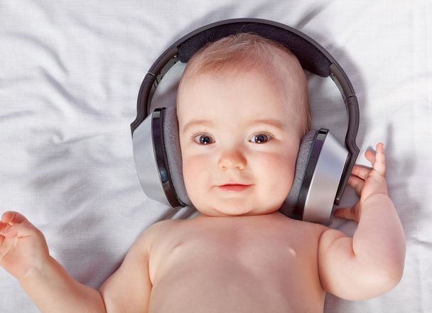 Cute baby listens to music through headphones. Close-up. - Valokuva, kuva