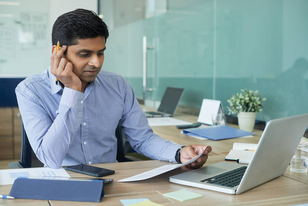 オフィステーブルで電話をかける肯定的なインドのビジネスマンの肖像画  - 写真・画像