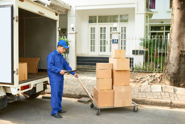 Працівник служби доставки завантажує свою вантажівку картонними коробками
 - Фото, зображення