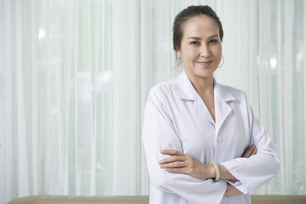 Souriant médecin vietnamien professionnel debout avec les bras croisés
  - Photo, image