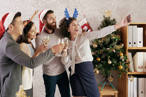 Happy Pretty bizneswoman biorąc selfie ze swoimi współpracownikami w biurze Christmas party - Zdjęcie, obraz