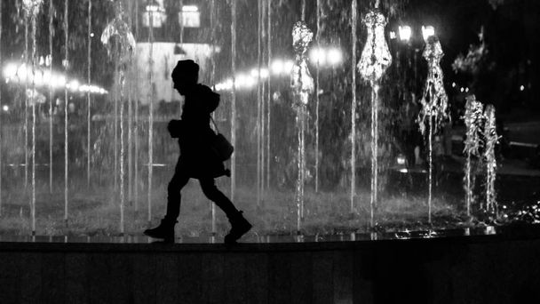 Çeşme sınırında yürüyen küçük bir kız çocuğu. Siyah ve beyaz siluet olarak biçimlendirilmiş - Fotoğraf, Görsel