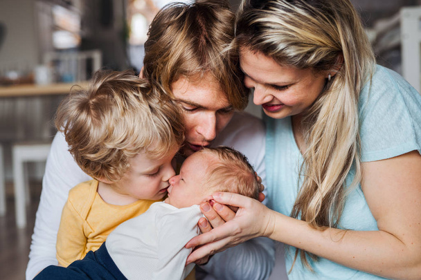 Young parents with newborn baby and small toddler son at home. - Foto, Imagen