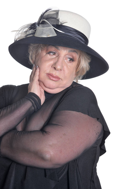 Senior vrouw in zwarte hoed poseren op witte achtergrond - Foto, afbeelding