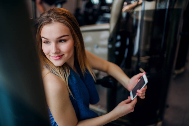 A portrait of young girl or woman with smartphone in a gym. - Foto, Imagem