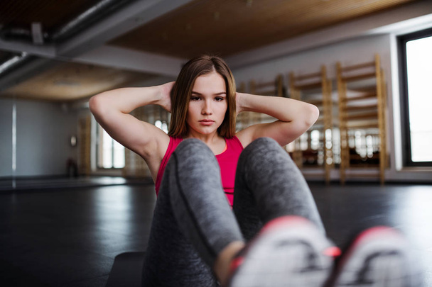 A portrait of young girl or woman doing exercise in a gym. - Foto, afbeelding