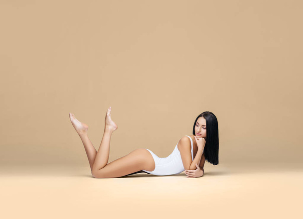 Attractive and sporty woman posing in white swimsuit. Fit and athletic body. Beautiful girl in swimsuit. Fitness, diet, healthcare and weight loss concept. - Zdjęcie, obraz