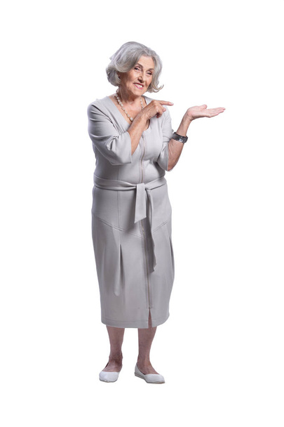 портрет красивой пожилой женщины, показывающий что-то на белом фоне
 - Фото, изображение