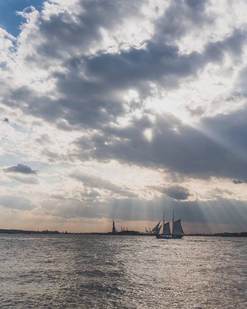 Boat traveling past Statue of Liberty at Sunset, in New York Cit - Photo, Image