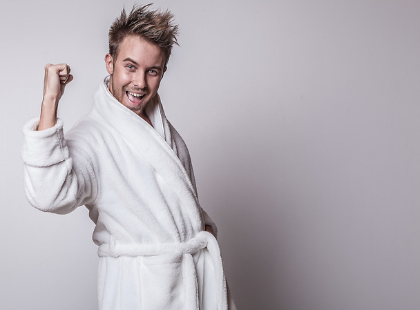 Handsome smiling young man in luxurious bathrobe. - Foto, afbeelding