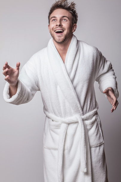 Handsome smiling young man in luxurious bathrobe. - 写真・画像