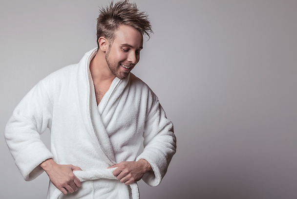Handsome smiling young man in luxurious bathrobe. - Photo, image