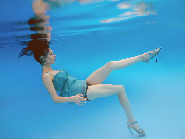 surreal, concept, art portrait of beautiful gorgeous brunette young woman with make up underwater in the swimming pool on blue background  - Valokuva, kuva