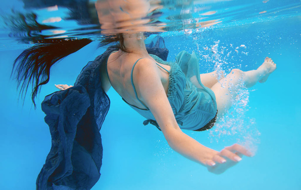 surreal, conceito, retrato de arte de bela jovem morena linda com maquiagem subaquática na piscina em fundo azul
  - Foto, Imagem