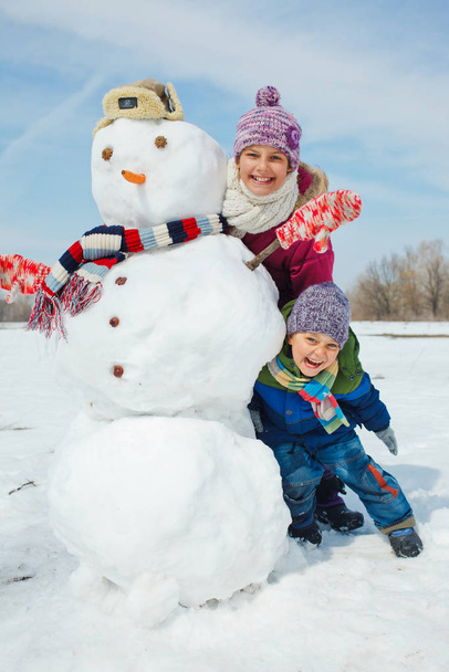 Happy beautiful children with snowman outside in winter time - Φωτογραφία, εικόνα