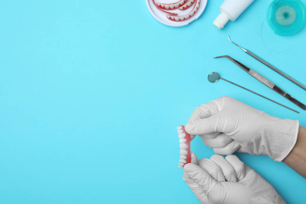 Dentist holding tooth prosthesis on color background, top view. Space for text - Foto, afbeelding