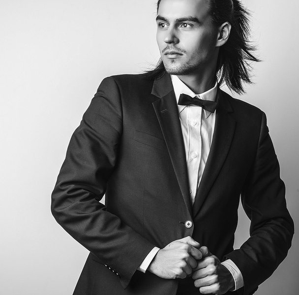 Elegant young handsome long-haired man in costume. Studio fashion portrait. - Fotó, kép