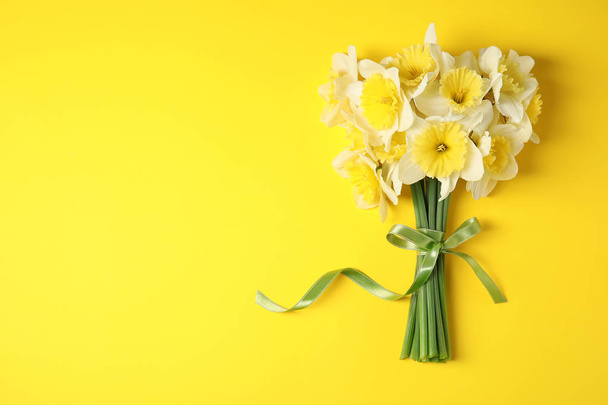 Bouquet of daffodils on color background, top view with space for text. Fresh spring flowers - Zdjęcie, obraz