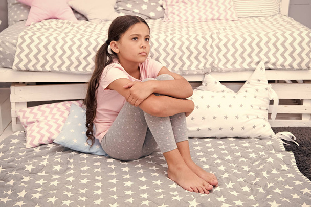Sad concept. Sad little girl. Sad child sit on bed. Sad kid in bedroom at home. I want to play - Photo, Image