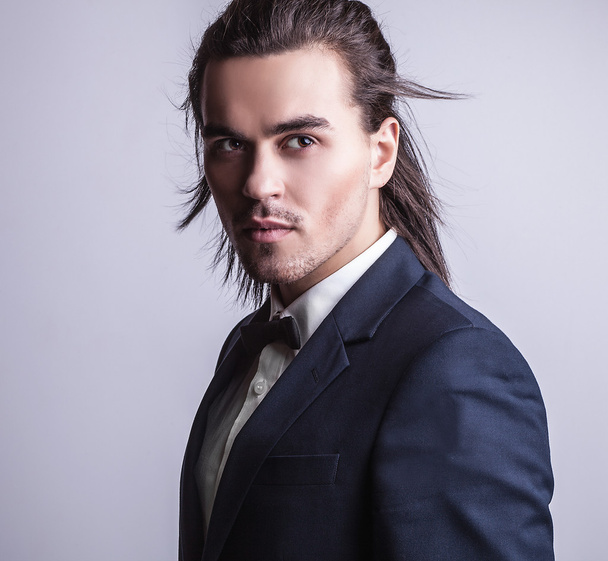 Elegant young handsome long-haired man in costume. Studio fashion portrait. - Foto, Bild