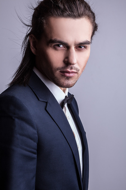 Elegant young handsome long-haired man in costume. Studio fashion portrait. - Foto, immagini