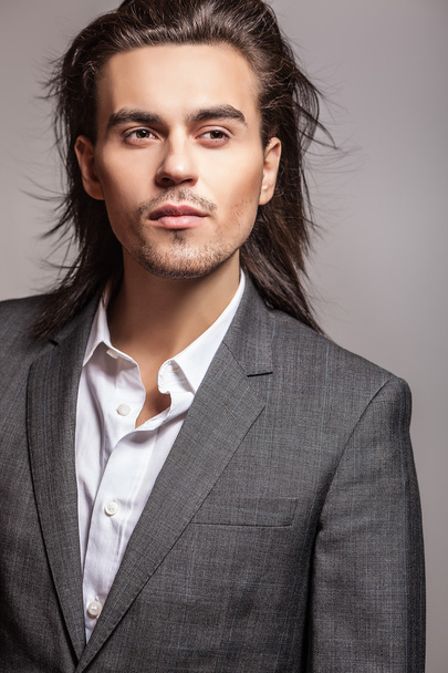 Elegant young handsome long-haired man in costume. Studio fashion portrait. - Zdjęcie, obraz
