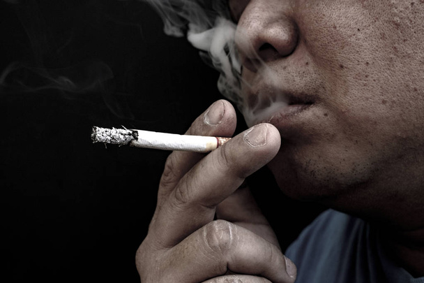 Mann raucht eine Zigarette, Bild der Zigarette in der Hand mit Rauch - Foto, Bild