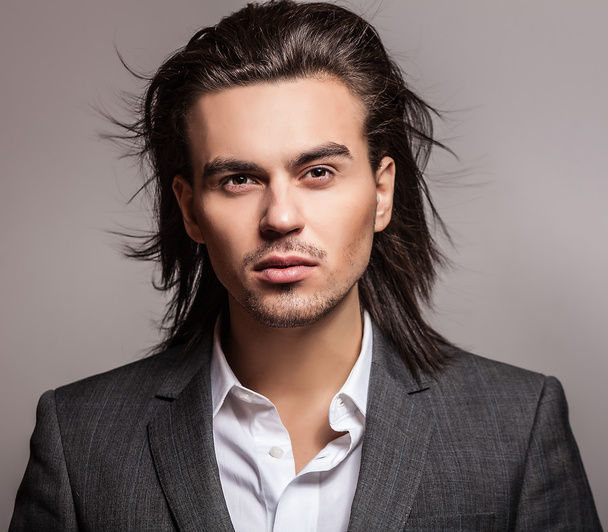 Elegant young handsome long-haired man in costume. Studio fashion portrait. - 写真・画像