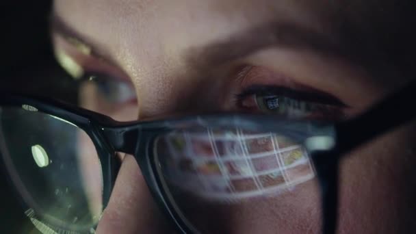 Woman in glasses looking on the monitor and surfing Internet. The monitor screen is reflected in the glasses - Metraje, vídeo