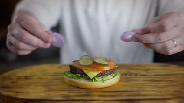 Şef burger pişirir ve içine kırmızı soğan halkaları koyar, fast food restoranda hamburger yapma, 4k Uhd 60p Prores Hq 422 - Video, Çekim