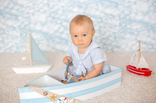 Cute toddler baby boy in wooden boat, playing with fishes, starf - Foto, immagini
