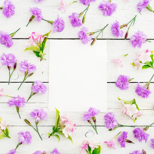 rosa Blumen mit Papierkarton auf weißem Holzhintergrund. flache Lage, Draufsicht - Foto, Bild