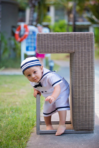 Όμορφο νήπιο αγόρι, ντυμένο σαν ναύτης, παίζοντας στην παραλία - Φωτογραφία, εικόνα