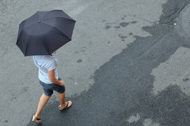 Nainen kävelee kadulla sateenvarjon kanssa
. - Valokuva, kuva