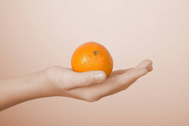 On a children's palm the orange tangerine lies - Foto, Imagem