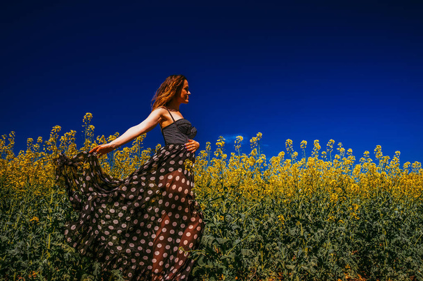 Женщина в платье позирует на поле рапса
 - Фото, изображение