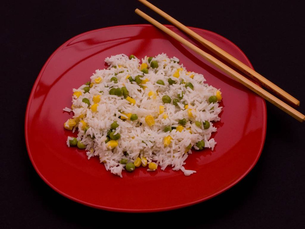 Rice on a red plate with chop-sticks. - Фото, изображение