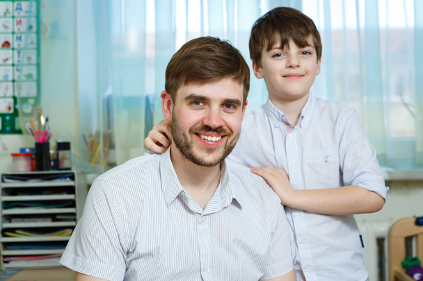 Retrato de padre e hijo de 8-10 años en habitación de niños, riéndose, abrazándose, divirtiéndose. Concepto de relaciones familiares felices
 - Foto, Imagen