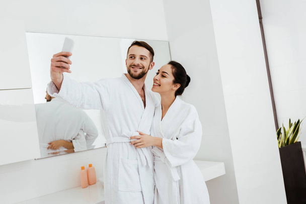 homme gai prenant selfie tout en se tenant avec petite amie dans la salle de bain
  - Photo, image