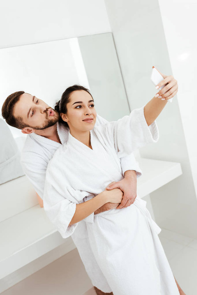 homme gai avec visage de canard prenant selfie tout en embrassant petite amie dans la salle de bain
  - Photo, image