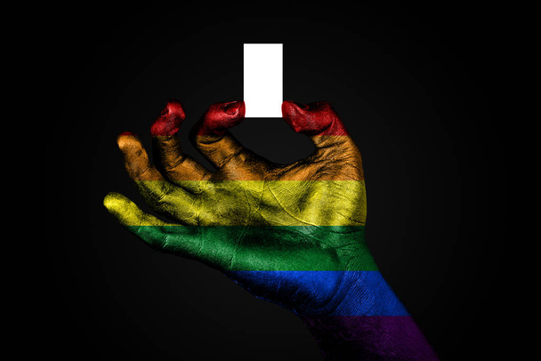 hand met een geschilderde vlag regenboog houden van een klein wit blad met ruimte voor een inscriptie, mock up - Foto, afbeelding