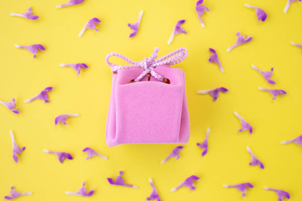 Pink gift box on a yellow background with flowers. Festive concept.  Flat lay, top view  - Φωτογραφία, εικόνα
