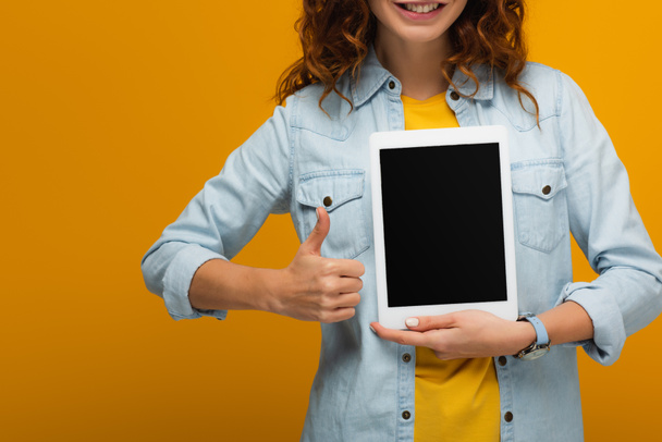 cropped view of cheerful curly woman holding digital tablet with blank screen and showing thumb up isolated on orange  - Φωτογραφία, εικόνα