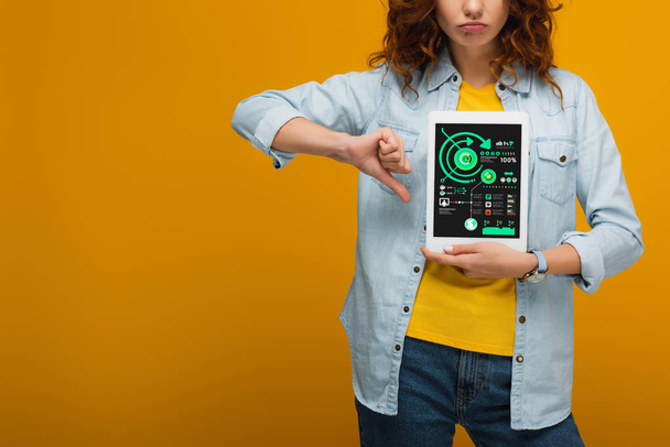 cropped view of sad curly woman holding digital tablet with charts and graphs on screen and showing thumb down on orange  - Photo, Image