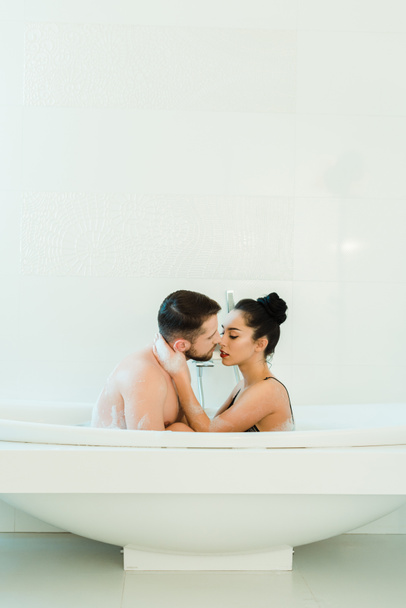 брюнетка жінка обіймає красивого без сорочки чоловіка у ванній
  - Фото, зображення