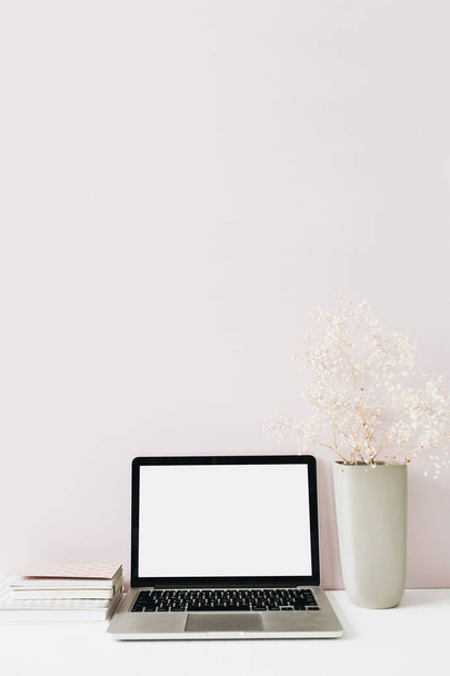 Laptop and flowers bouquet on pink background. Front view minimal modern home office desk workspace. Blank screen mock up hero header. Blog, social media, website template. Girl boss concept. - 写真・画像