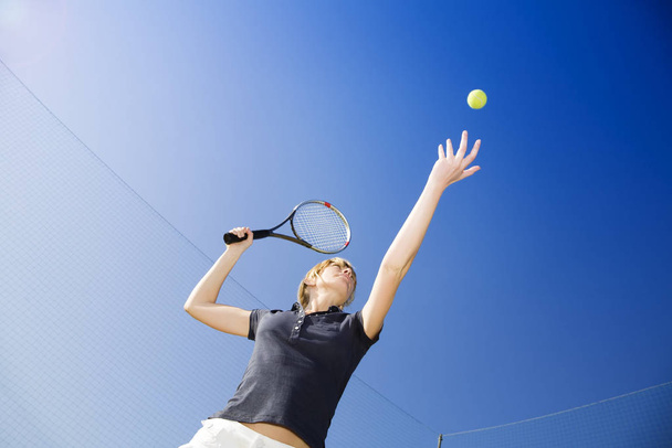 blond woman playing tennis, about to hit the ball. Copy space - Фото, зображення