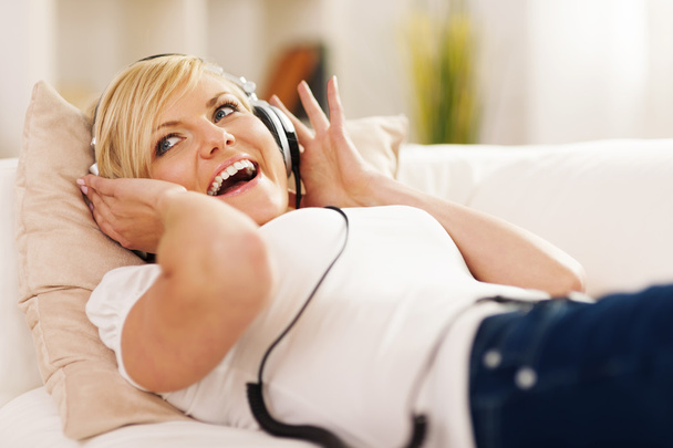 Happy woman listening to music on sofa - Photo, Image
