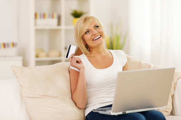 Souriant jeune femme utilisant un ordinateur portable et tenant la carte de crédit
 - Photo, image